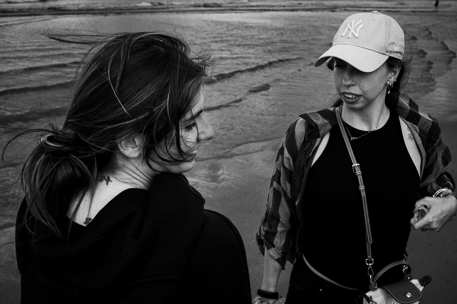 Due ragazze parlano sulla riva, una con il cappellino