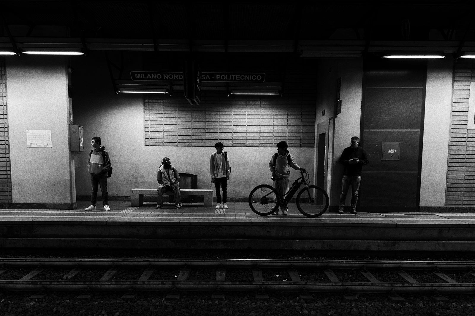 Una banchina con poche persone in attesa e una bicicletta