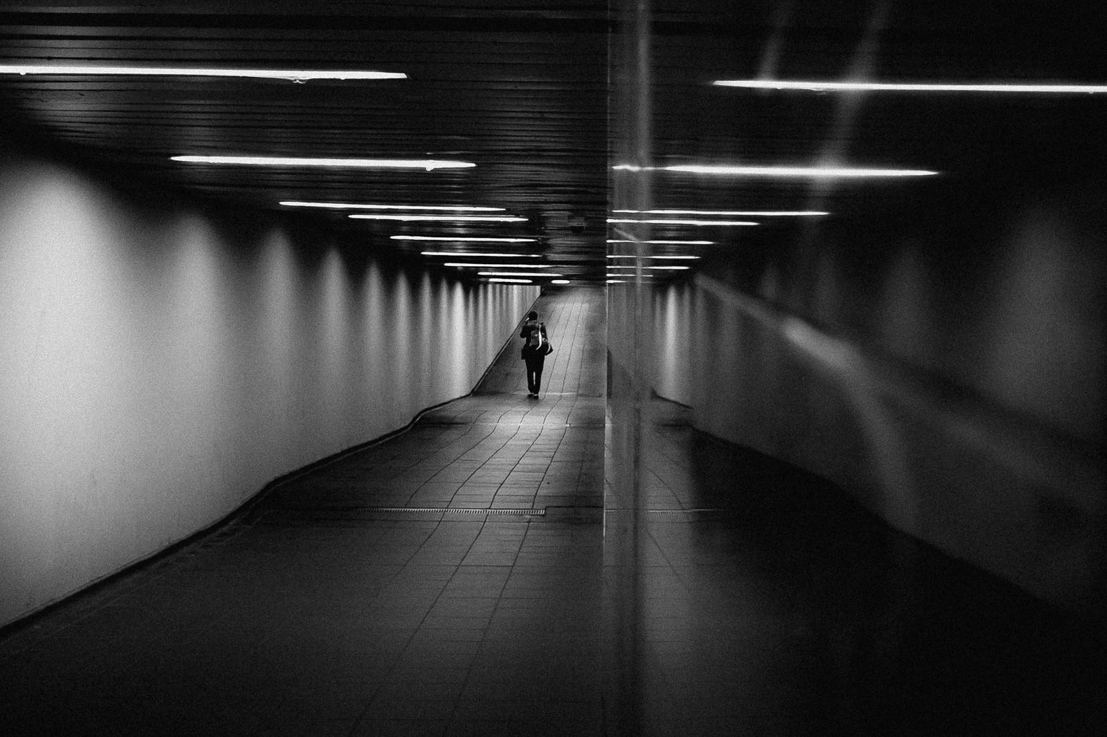 Un lungo corridoio sotterraneo con una persona in fondo
