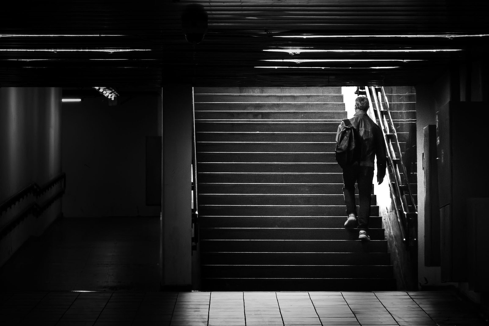 Una persona sale le scale di un sottopassaggio, in controluce