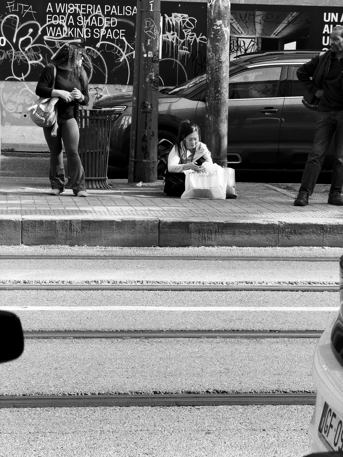 Persone in attesa alla fermata, dall'altra parte della strada