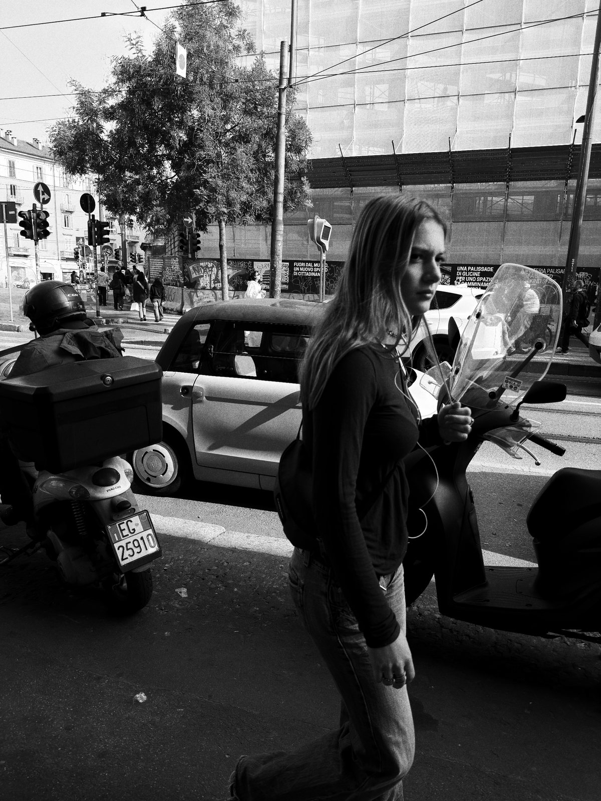 Una ragazza cammina tra le auto e gli scooter