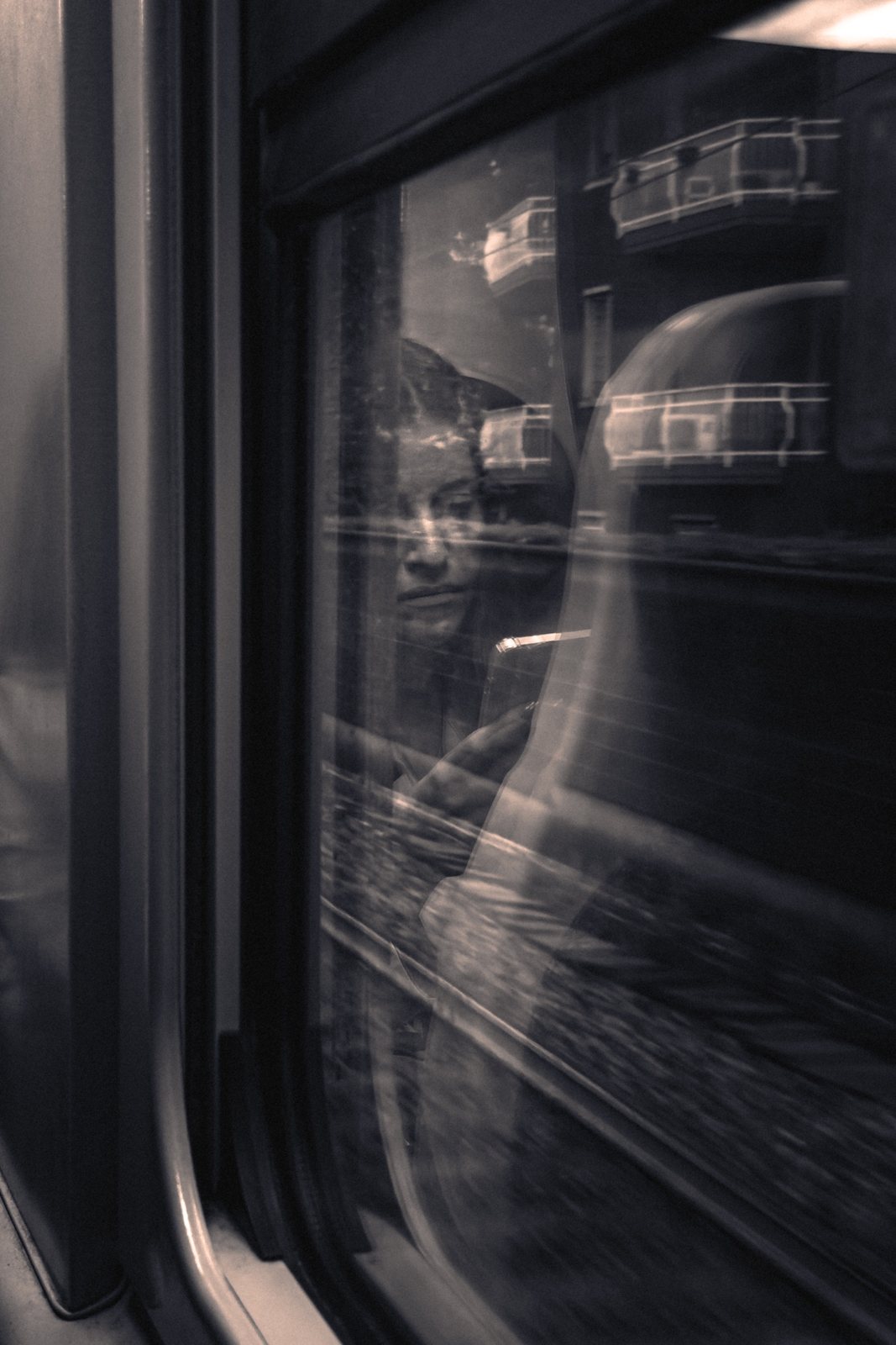Un volto riflesso nel finestrino del treno